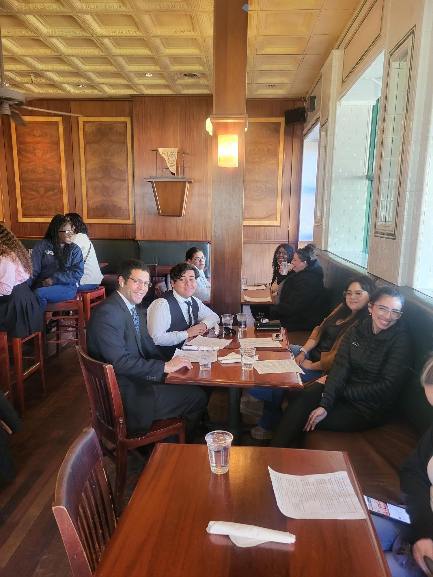 People sitting at a wooden table in a restaurant with menus and glasses of water.